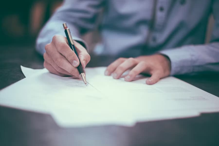 Close-up of a person signing a contract document